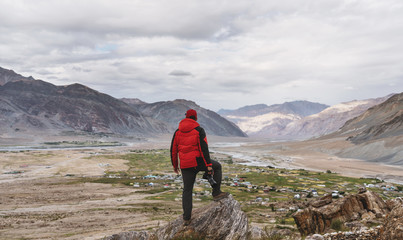 Wall Mural - a man in red jacket standing on mountain summit, and mountains view. travel lifestyle, adventurous, 