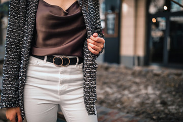 Street, office, bright style. Young woman in black jacket, white pants with a black belt