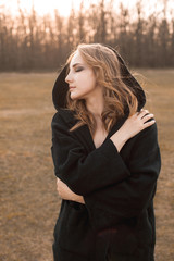 Wall Mural - Portrait of the young woman in black cape on the field. Profile