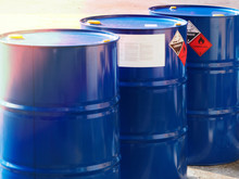 The Close-up Shot Of Blue Color Hazardous Dangerous Chemical Drum Barrels ,have Warning Labels Of Corrosive & Flammable Liquid In Daylight On Daytime.