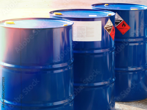 Fotografía the close-up shot of blue color hazardous dangerous chemical drum barrels ,have warning labels of corrosive & flammable liquid in daylight on daytime