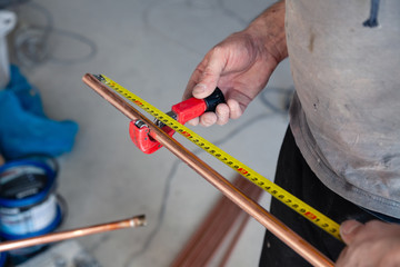 Wall Mural - Closeup worker plumber master measures copper pipes with roulette tape, cut pipe with cutter. Concept installation, changing pipeline, repair, leakage, breaking sewage