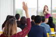 © iammotos - young businesswoman raising hand  to question from Speaker in Seminar. Group Meeting . Conference  Concept . Rear back view