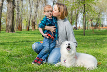 Mom And Her Son With A Fluffy Samoyed Dog In A Park In Spring
