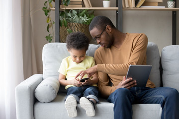 Wall Mural - African father helping little son explain new app or game