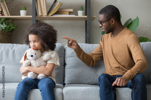 Cuadros en Lienzo African dad scolding for discipline stubborn daughter sitting on sofa