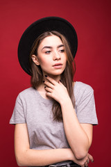 Wall Mural - Portrait stylish girl wearing black hat isolated over red background