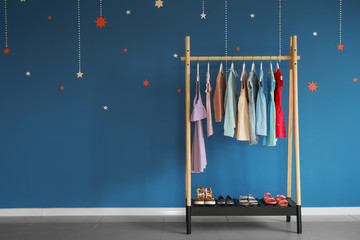 Rack with children's clothes near color wall