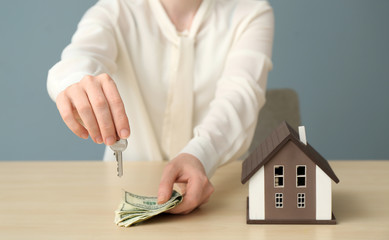 Poster - Real estate agent with key, money and model of house at table