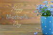 Happy Mothers Day card with flowers in the cup on wooden background