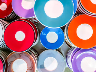 Top view and closeup colorful heap of ceramic coffee cup saucers fit on screen background and wallpaper.