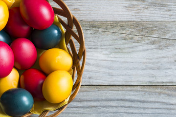 Wall Mural - Traditional colored Easter eggs on wicker basket with wooden background