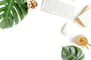 Flat lay home office desk. Female workspace with computer,  tropical palm leaves  Monstera, accessories on white background. Top view feminine background. 