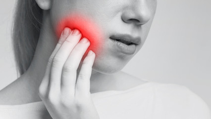 Young woman feeling toothache touching her cheek