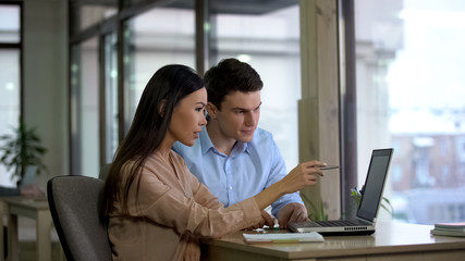 Wall Mural - Female and male co-workers reading email laptop, planning strategy, discussion