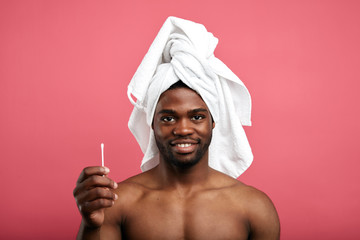 Wall Mural - handsome cheerful bearded man standing isolated over pink background, holding cotton swabs, expresses positive emotion. health care concept.