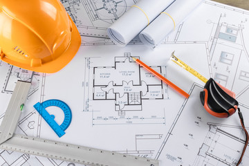 Orange helmet, pencil, architectural construction drawings, tape measure. The concept of architecture, construction, engineering, design. Copy space.