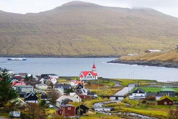 View of iconic Scandinavian church with red roof. Located in Sandavágur village, Vágar Island. Popular tourist spot in Faroe Islands, Denmark, Europe.