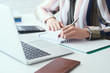 © cameravit - Closeup business woman left hand making notes with silver pen in office. Business finance savings loan and credit concept.