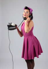 Wall Mural - Beautiful woman in purple dress with vintage black phone.