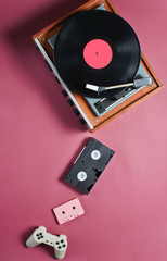 Retro items on red background. Vinyl player, video, audio cassette, gamepad. Pop culture, 80s. Top view