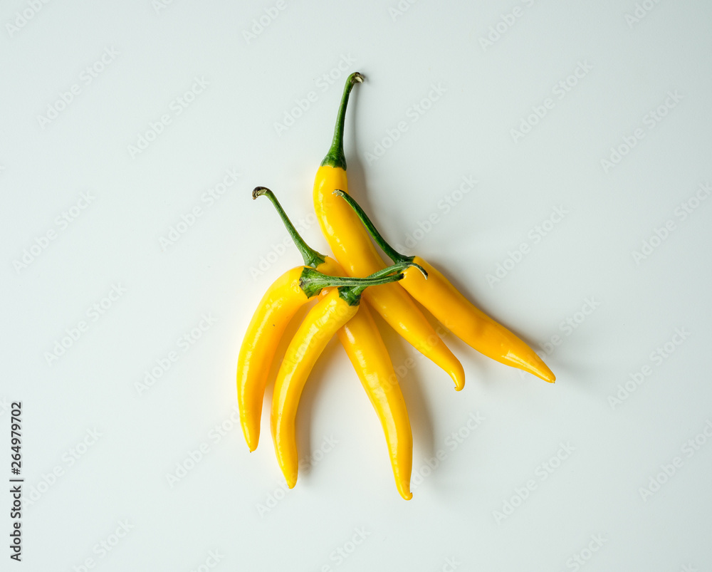 Żółte papryczki chili leżące na białym tle. Ostry dodatek do potrawy.  - obrazy, fototapety, plakaty 