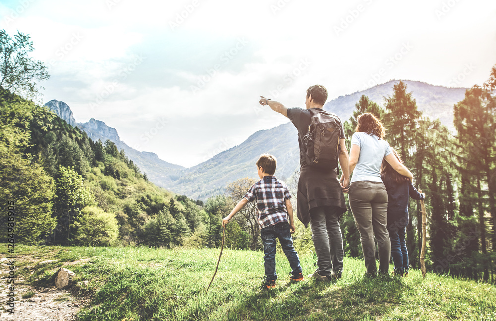 family on a green meadow looking at the mountain panorama - obrazy, fototapety, plakaty 