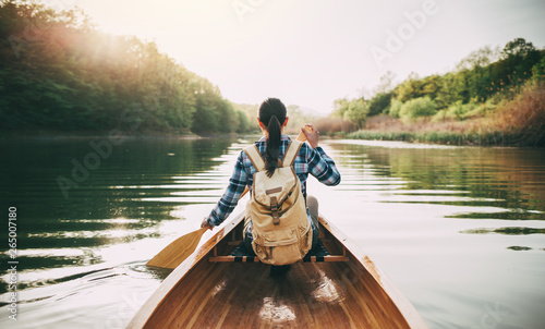 Cuadros en Lienzo Rear view of travel woman rowing the boat at sunset