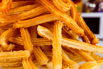 Pile of freshly made deep fried churros sweet pastry traditional for Spain Portugal Latin America at street cafe. Scrumptious treat appetizing golden crust. Authentic city life atmosphere street food