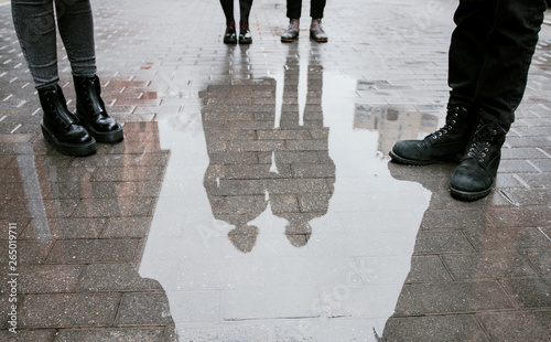 Cuadros en Lienzo Reflection of a group of people, four pairs of legs and a pair guy and girl in a