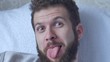 © smartbobert - A young bearded man poses a face showing tongue hamming smiling and laughing closeup