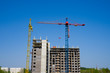© mozyr - Construction crane on the background of a multi-storey building under construction