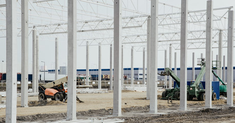 Concrete poles for the construction of the warehouse. Building a new warehouse, industrial concept and construction. Development and modernity. Setting stable pillars for new buildings.