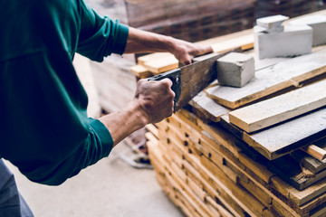 Close up on the construction worker using the hand saw to manually cut the brick insulation material concrete stone