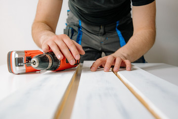 Poster - The man wraps wooden boards on the work table. The concept of DIY and renovation of new things. A man tinkering at home, working with wood.