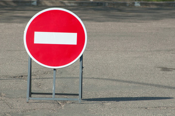 One red no entry traffic sign on the road in the city. The portable sign is mounted on a metal base. Copy space.