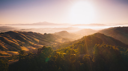 Aerial panoramic background. Sunlight shining on beautiful rolling hills with fog