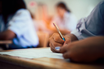 Hand of students taking exam with stress in classroom