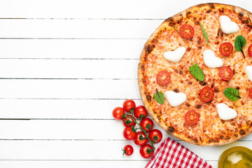 Italian pizza with mozzarella, cherry tomatoes and sauce on white wooden planks background. Top view with copy space for text