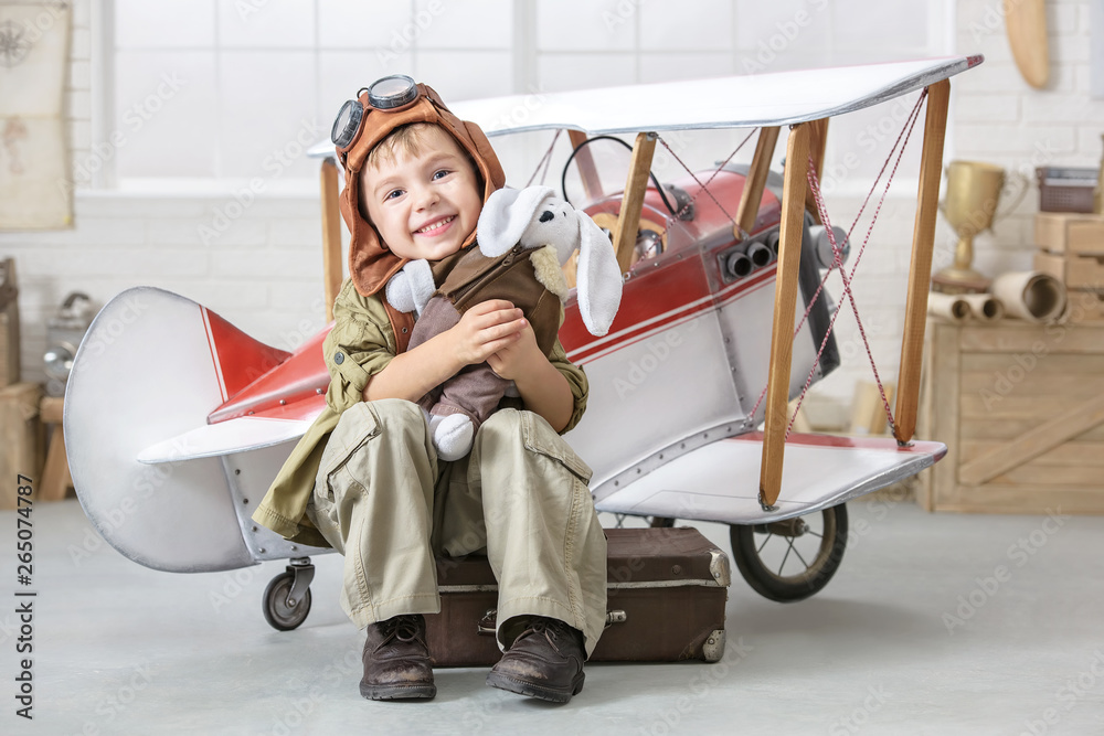 Little boy in the image of the pilot near the toy-plane - obrazy, fototapety, plakaty 