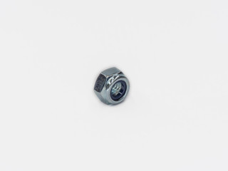 Zinc plated self locking hexagonal metric stop nut on white.