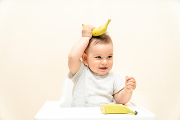 Funny little toddler eating banana in a high chair copy space food baby