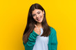 © luismolinero - Teenager girl over yellow wall giving a thumbs up gesture