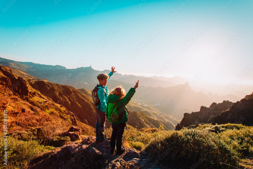 happy boy and girl travel in mountains at sunset - obrazy, fototapety, plakaty 