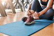 © Friends Stock - Comfort in everything. Cropped image of sporty woman tying shoelaces while sitting on a mat at gym