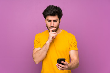 Handsome over isolated purple wall thinking and sending a message