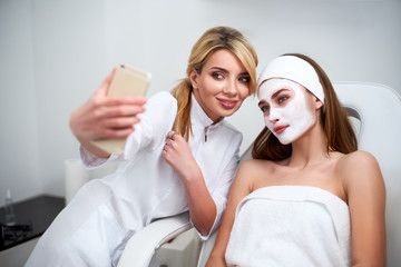 beautician blogger making selfie with client after applying facial mask for healthy skin. attractive