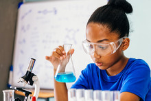 Young African American Mixed Kid Testing Chemistry Lab Experiment And Shaking Glass Tube Flask Along With Microscope - Science And Education Concept