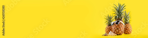 Fotomural Creative pineapple looking up with sunglasses and shell isolated on yellow backg