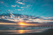 Sun Rising Over Horizon And Pier, Beach Illuminated With Sunlight, Beautiful Sky Reflected On The Beach. Jacksonville Florida, USA.